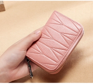 Dettaglio del porta carte in pelle rosa con cuciture trapuntate e zip in metallo