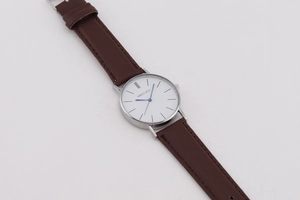 Macro detail of MREURIO minimalist white dial watch with brown leather strap and silver case