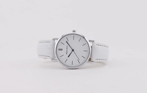 Detail of minimalist silver quartz watch with white leather strap and MREURIO dial logo