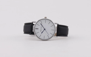 Close-up of minimalist white dial watch with blue hands and black leather strap