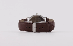Detail view of the brown leather watch strap with a polished silver metal pin buckle