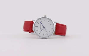 Detail view of red leather strap watch with minimalist white dial and blue hands