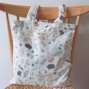 Close-up of floral canvas tote bag with elephant pattern on a wooden chair