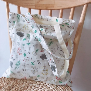 Floral canvas tote bag with rabbit prints resting on a wooden chair in soft light