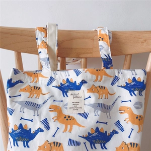 Detailed close-up of cotton tote bag featuring colorful cartoon dinosaur patterns on blue fabric