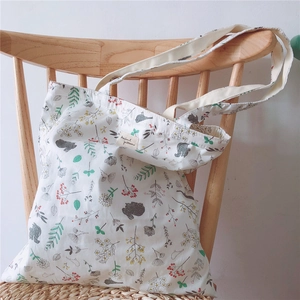 Close-up of floral animal patterns on white cotton tote bag hanging on a wooden chair