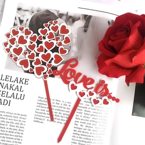 Detail of acrylic cake topper with Love is text and red hearts on a magazine background