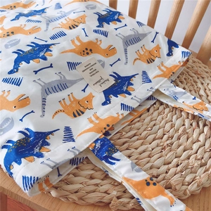 Detail of canvas tote bag featuring orange and blue dinosaur patterns on woven mat