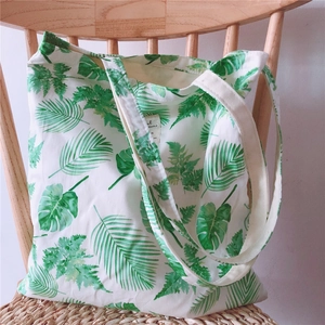 Detail view of tropical leaf pattern and woven handle on a canvas tote bag