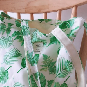 Detail of floral canvas tote bag featuring green tropical leaf prints and woven fabric label