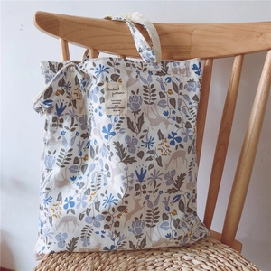 Detailed floral canvas tote bag with deer pattern hanging on a wooden chair