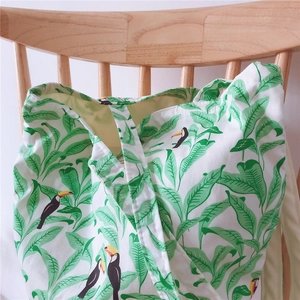 Detail of canvas tote bag featuring green tropical leaves and colorful toucan print