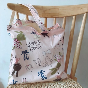 Detailed view of pink canvas tote bag featuring cute cartoon rabbit prints and art text