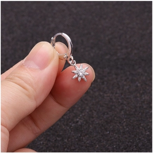 Silver micro-pave zircon sunflower hoop earring with star pendant held by fingers