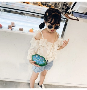 Girl modeling a green lip-shaped crossbody bag with a gold chain in a bright cafe setting