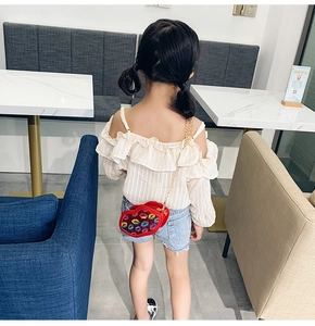 Detailed view of child fashion outfit featuring red sequined lip-shaped chain bag