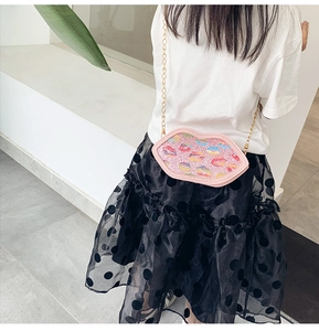 Detail of pink glitter lip-shaped crossbody bag with colorful prints and gold chain