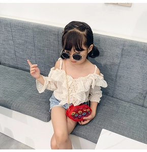 Kid girl wearing a red sequined lip-shaped crossbody bag with a golden chain strap