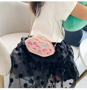 Close-up of pink glitter lip-shaped crossbody bag with gold chain strap for kids
