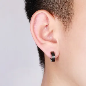 Minimalist matte black stainless steel huggie earrings worn on ear for a unisex style