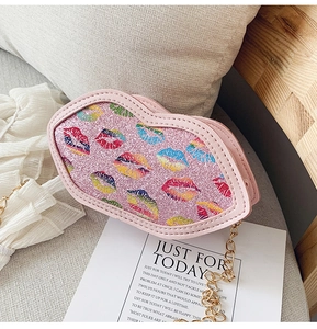 Close-up of pink glitter lip-shaped crossbody bag with gold chain on soft background