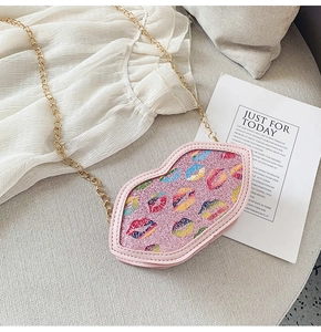 Detailed macro of pink glitter lip-shaped bag with colorful prints and gold chain strap
