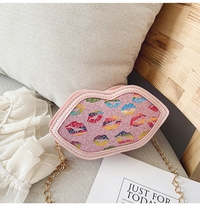 Detail of pink lip-shaped bag with glitter finish and golden chain strap for kids