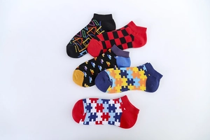 Flat lay view of five pairs of men's low-cut socks with colorful geometric and plaid patterns