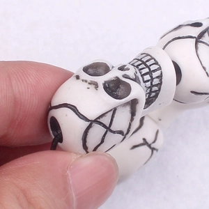 Close-up of white skull beads crafted from faux yak bone on a punk stretch bracelet