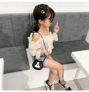 Cute black cartoon bear crossbody bag for children shown on a model in a lounge area
