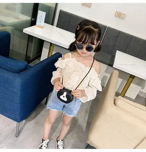 Flat lay of girl's summer outfit with beige striped top and blue denim shorts