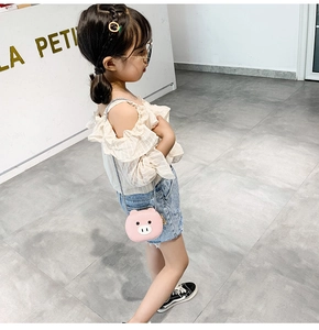 Pink cartoon pig crossbody bag shown on a young girl in a bright retail store