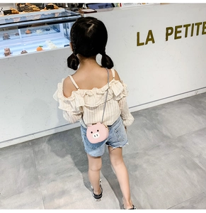 Rear view of a girl wearing a pink round pig-shaped mini crossbody bag in a store