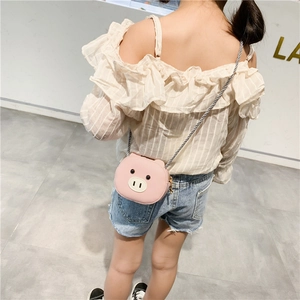 Pink pig-shaped kids crossbody bag in PU leather, shown on a child in a bright room