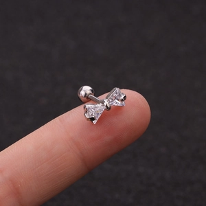 Macro detail of silver bow cartilage stud earring with cubic zirconia and ball back