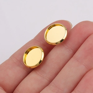 Polished 12mm gold plated stainless steel earring base studs held on a fingertip