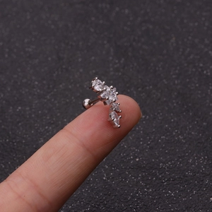 Macro detail of curved ear cartilage stud with white zircon crystals held by hand