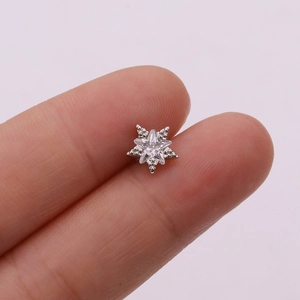 Macro shot of silver star stud earring with clear zircon inlay on fingers for size guide