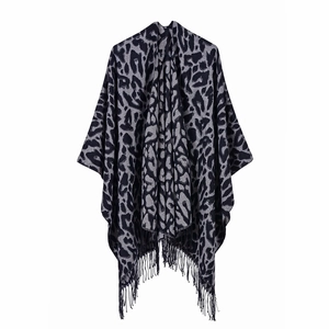 Close-up detail of knitted leopard print shawl with fringe on a white background