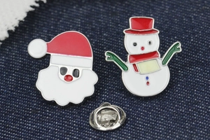Detail of Christmas enamel pins set featuring Santa Claus and snowman on denim fabric
