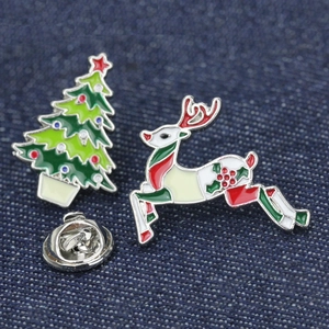 Detailed close-up of Christmas enamel pins featuring a reindeer and tree on denim fabric