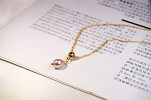 Detail of pink teardrop freshwater pearl pendant on a gold titanium steel necklace