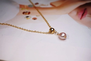 Detailed view of pink freshwater pearl pendant on a gold titanium steel necklace chain