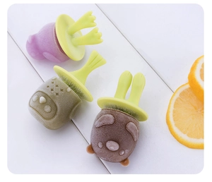 Three cute animal-shaped silicone ice pops including pig, frog, and bear on a wooden table