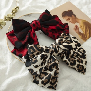 Detailed texture of satin leopard print bow hair clips on elegant marble tray display