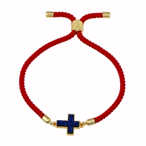 Dettaglio del bracciale rosso intrecciato con croce glitter blu e fibbia dorata regolabile