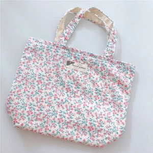 Detail of floral cotton tote bag showing pink flower pattern and woven label text