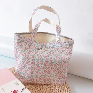 Detailed view of floral cotton tote bag with zipper closure and brand label on white background