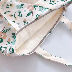 Detailed close-up of zipper closure and floral print on a cotton canvas tote bag
