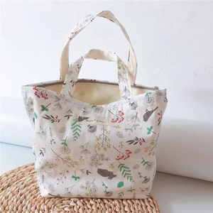 Detail of canvas tote bag featuring bird and botanical prints with dual handles